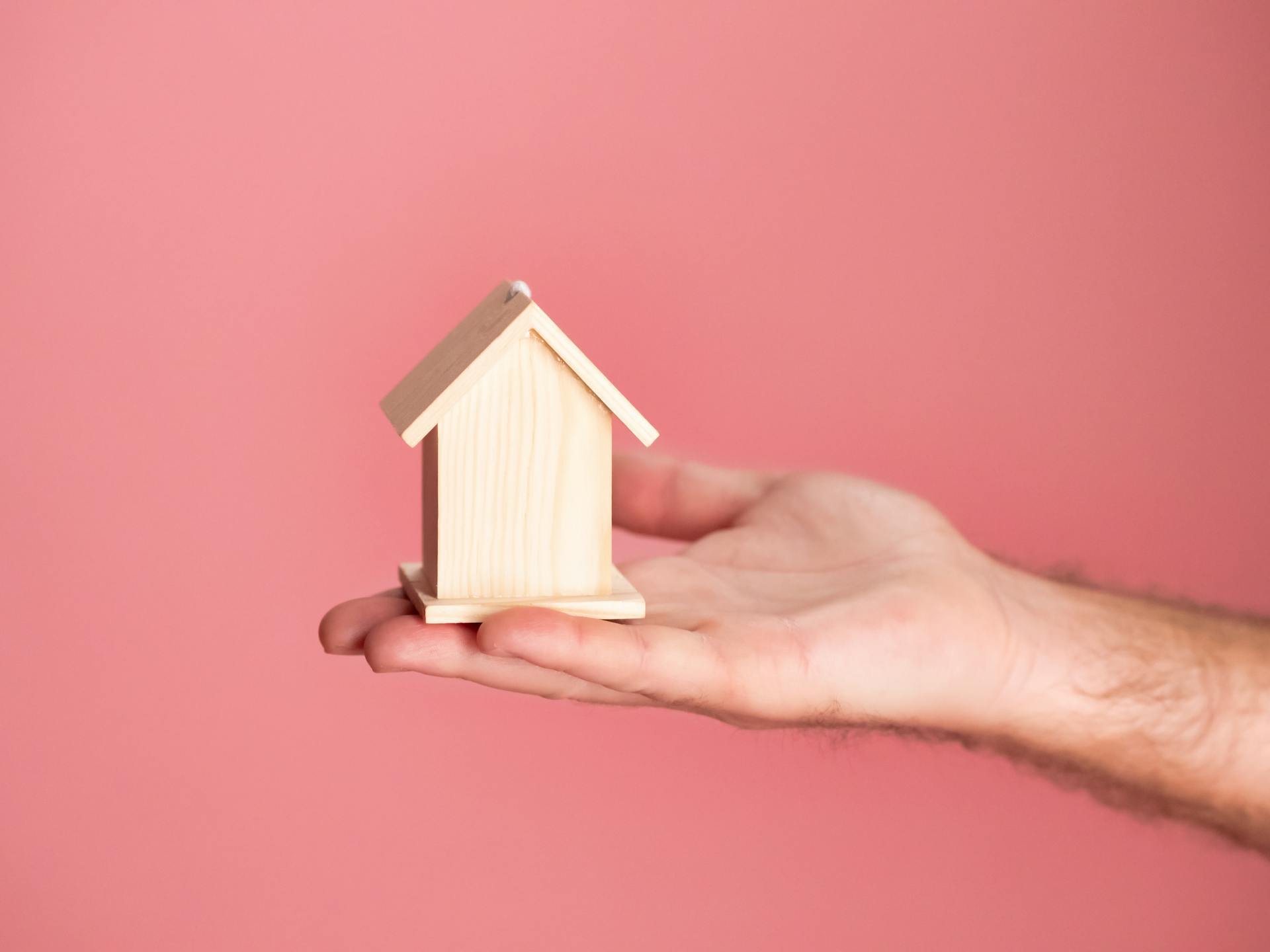 Hand holding a small wooden house model